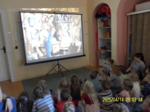 Foto von Kindern, wie sie vor einer Leinwand stzen und einen Film schauen.